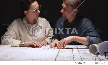 Architects and engineers collaborating on a new building project, planning structural details and design concepts using blueprints and a scaled architectural model on a desktop Architects and engineers collaborating on a new building project, planning structural details and design concepts using blueprints and a scaled architectural model on a desktop 138484323