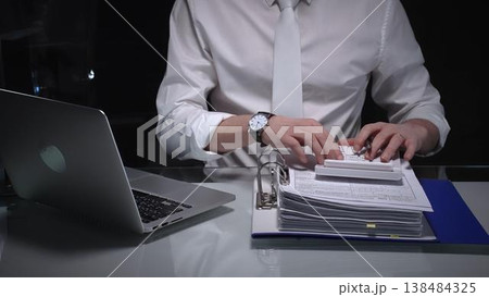 Businessman studying financial report data with calculator and laptop, conducting detailed audit and analysis. Audit and taxes in business Businessman studying financial report data with calculator and laptop, conducting detailed audit and analysis. Audit and taxes in business 138484325