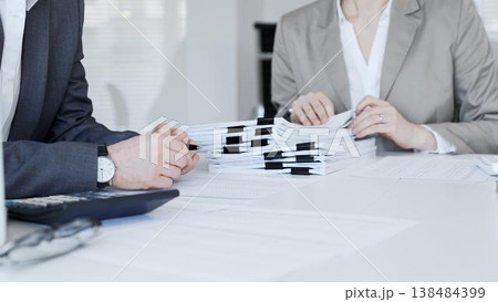 Business people hands reviewing stacks of financial papers and agreements, discussing data during an office meeting. Audit and taxes in business Business people hands reviewing stacks of financial papers and agreements, discussing data during an office meeting. Audit and taxes in business 138484399