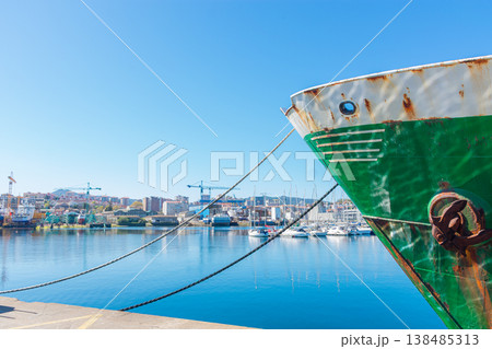 Bow of a green fishing boat moored in the port of Vigo with the industrial shipyards in the background in Galicia Bow of a green fishing boat moored in the port of Vigo with the industrial shipyards in the background in Galicia 138485313