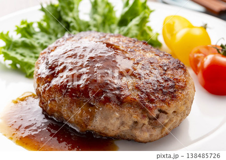 白い皿に盛り付けたシンプルなハンバーグ テーブル上 手作り感のある肉料理 洋食の定番 138485726