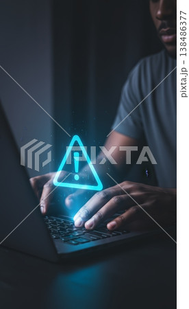Man typing on a laptop, encountering a prominent glowing warning sign hovering above the keyboard, representing a computer error, alert, or cybersecurity issue 138486377