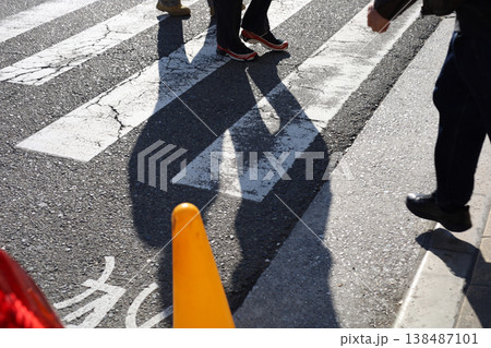 People walking across a zebra crossing on a sunny day. People walking across a zebra crossing on a sunny day. 138487101