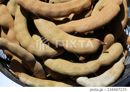 A pile of fresh tamarind pods in a basket. 138487235