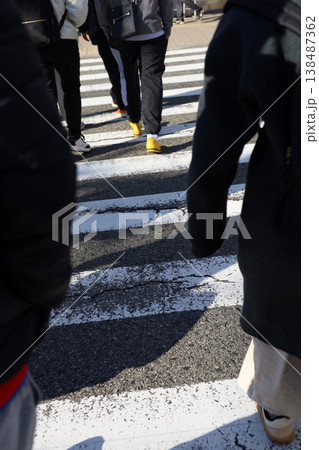 People walking across a zebra crossing on a sunny day. People walking across a zebra crossing on a sunny day. 138487362