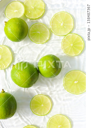Fresh green lime slices floating in clear water with ripples texture. Fresh green lime slices floating in clear water with ripples texture. 138487367