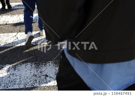 People walking across a zebra crossing on a sunny day. 138487491