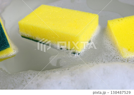 A dishwashing sponge floats in the foamy water of a dishwashing solution. A dishwashing sponge floats in the foamy water of a dishwashing solution. 138487529
