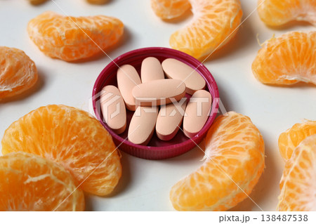 Vitamin C pills surrounded by fresh mandarin orange segments. Vitamin C pills surrounded by fresh mandarin orange segments. 138487538