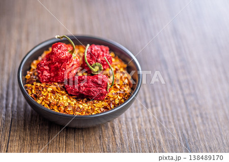 Dried Ghost Peppers And Red Chili Flakes In Bowl On Rustic Wooden Table Dried Ghost Peppers And Red Chili Flakes In Bowl On Rustic Wooden Table 138489170