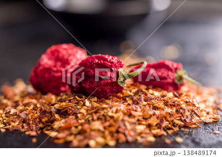 Dried Red Chili Peppers and Crushed Red Pepper Flakes Close-Up on Dark Surface 138489174
