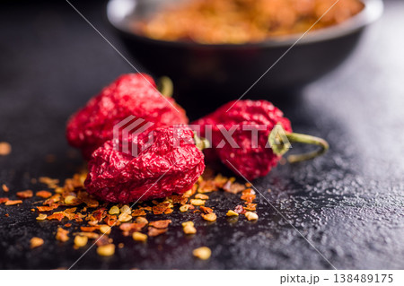 Dried Red Chili Peppers and Crushed Red Pepper Flakes Close-Up on Dark Surface 138489175