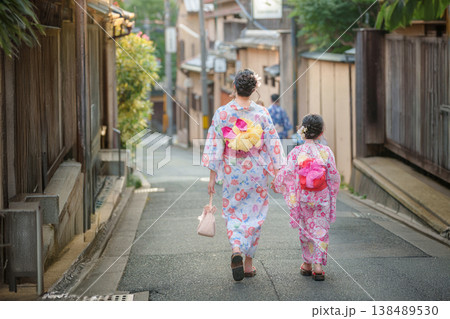 京都の古い町並みを手をつないで歩く浴衣姿の親子（母と娘）の後ろ姿。 138489530