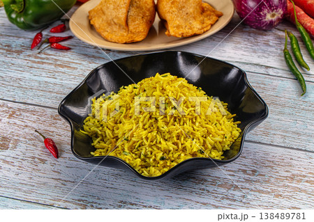 Bowl of yellow basmati rice pilaf with herbs, served with appetizers on a rustic wooden table. Bowl of yellow basmati rice pilaf with herbs, served with appetizers on a rustic wooden table. 138489781