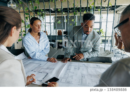 Multiracial architects examining construction plans together Multiracial architects examining construction plans together 138489886