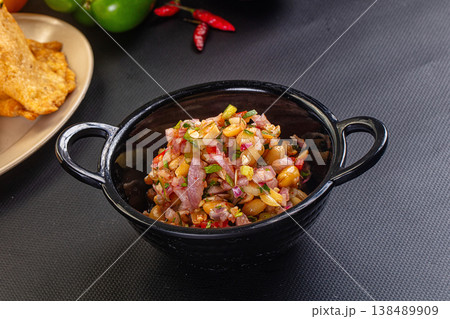 Spicy peanut and red onion salsa with cilantro and chili, served with fried chips. Spicy peanut and red onion salsa with cilantro and chili, served with fried chips. 138489909