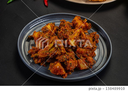 Traditional Indian potato and vegetable curry (Aloo Sabzi) served on a plate with fresh chilis. 138489910