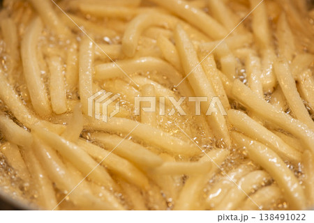 熱油の中で調理されるフライドポテト。黄金色に揚がった新鮮なポテトフライ。 138491022