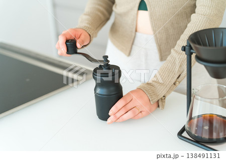 自宅のキッチンでコーヒーミルでコヒー豆を挽くアジア人女性 自宅のキッチンでコーヒーミルでコヒー豆を挽くアジア人女性 138491131