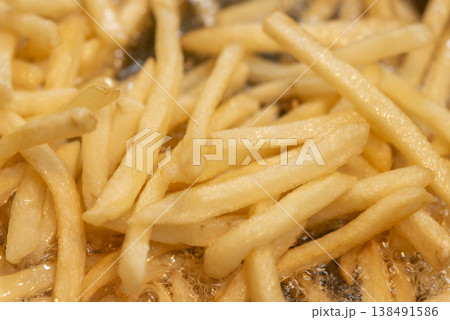 熱油の中で調理されるフライドポテト。黄金色に揚がった新鮮なポテトフライ。 138491586