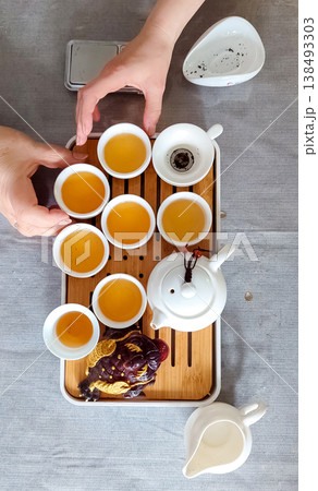 Traditional chinese tea ceremony gongfu cha with white ceramic teapot, cups and golden money frog on bamboo tray. Pouring oolong tea, mindful atmosphere, oriental culture and zen lifestyle. 138493303