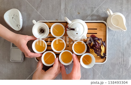 Traditional chinese tea ceremony gongfu cha with white ceramic teapot, cups and golden money frog on bamboo tray. Pouring oolong tea, mindful atmosphere, oriental culture and zen lifestyle. 138493304
