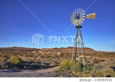 Vintage Windmill Desert Landscape and Mountains Under Clear Blue Sky Vintage Windmill Desert Landscape and Mountains Under Clear Blue Sky 138493352