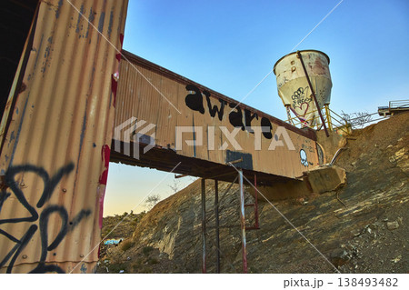 Abandoned Desert Mill Walkway With Graffiti and Rusted Tank at Sunset 138493482