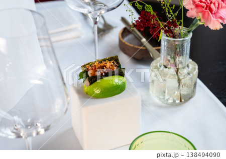 Refined presentation showcasing appetizer alongside sophisticated glassware and flowers Refined presentation showcasing appetizer alongside sophisticated glassware and flowers 138494090