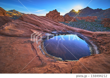 Redstone Dune Sunrise with Desert Tinaja Water Reflection and Sunburst in Vibrant Nevada 138494212