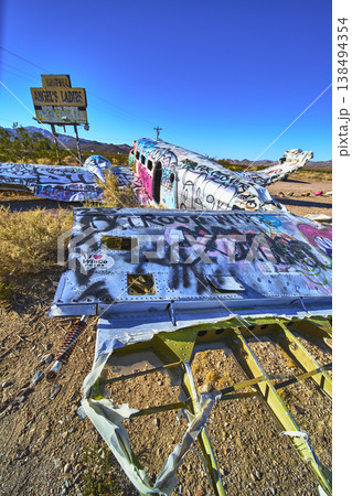Graffiti Covered Airplane Wreck and Roadside Sign in Nevada Desert Landscape 138494354