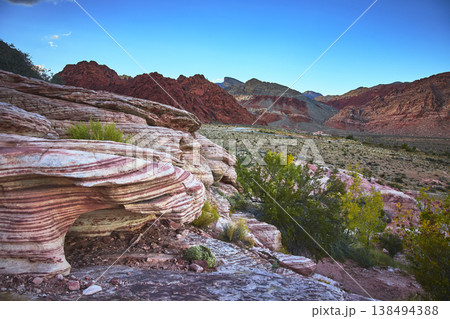 Red Rock Canyon Layered Sandstone Formations with Desert Vegetation and Distant Peaks Red Rock Canyon Layered Sandstone Formations with Desert Vegetation and Distant Peaks 138494388