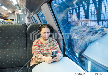 Smiling teenager girl with gallses and headphones in train Smiling teenager girl with gallses and headphones in train 138494656