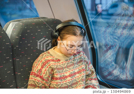 Smiling teenager girl with gallses and headphones in train Smiling teenager girl with gallses and headphones in train 138494869