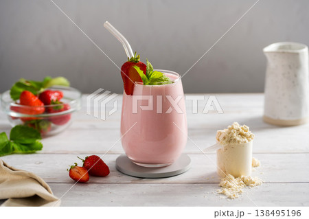 Pink strawberry smoothie in a glass and scoop of protein powder. Copy space 138495196