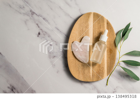 Rose quartz gua sha tool and oil bottle on wooden tray, face massage tool, beauty abstract photo. Copy space Rose quartz gua sha tool and oil bottle on wooden tray, face massage tool, beauty abstract photo. Copy space 138495318