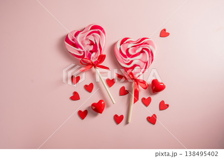 Valentine's Day festive background. Heart-shaped lollipops and heart confetti on pink background with copy space. Love concept Valentine's Day festive background. Heart-shaped lollipops and heart confetti on pink background with copy space. Love concept 138495402