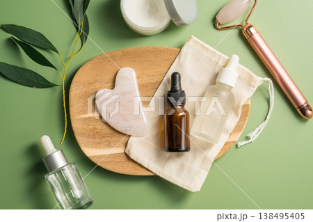 Rose quartz gua sha tool and face massage roller on green background, beauty abstract photo. Top view Rose quartz gua sha tool and face massage roller on green background, beauty abstract photo. Top view 138495405