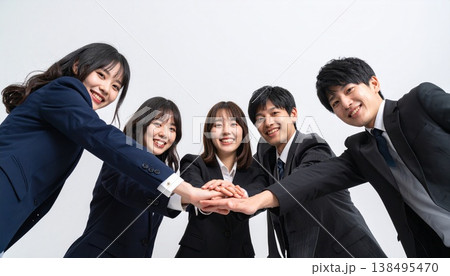 手を重ね合わせて団結するスーツ姿の男女5人のビジネスチーム 138495470