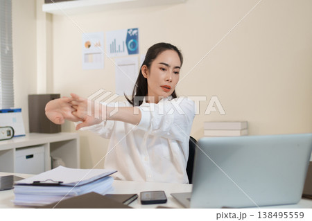 Businesswoman stretching arms to relieve work stress during busy office workday 138495559