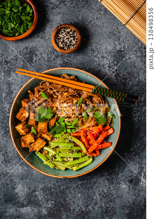 Soba noodles with vegetables and fried tofu in a bowl. 138498356