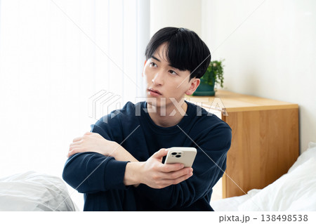 ベッドでスマホを見る若い男性 ベッドでスマホを見る若い男性 138498538