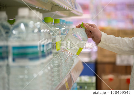 ペットボトル入りの水を選ぶ買い物客の手元 ペットボトル入りの水を選ぶ買い物客の手元 138499543
