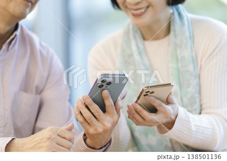 カフェでスマートフォンを持った中高年の男女の手元 カフェでスマートフォンを持った中高年の男女の手元 138501136