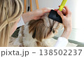 A girl combs and tidies up the beautiful face of a Shih Tzu dog. 138502237