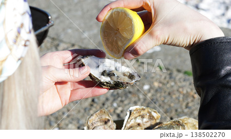 A close-up of a girl squeezing lemon onto a fresh oyster A close-up of a girl squeezing lemon onto a fresh oyster 138502270