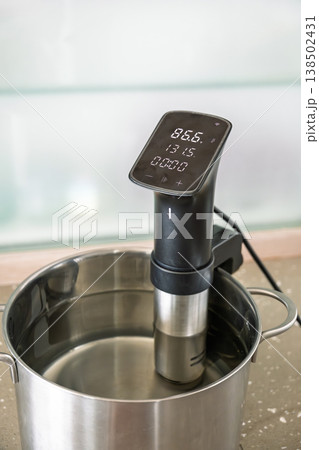 Sousvide immersion circulator heating water in pot on kitchen counter cooking process 138502431
