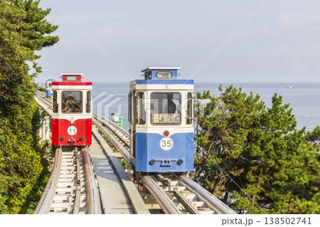 Colorful oceanfront capsule cars travel along an elevated coastal rail, offering scenic seaside views and a relaxed tourism experience over the water. High quality photo 138502741