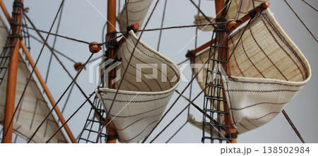 Masts of Sailing Ship. Closeup Detail of Mast and Sails. Crows nest, mast, and canvas sails can be seen in this closeup detail of an old time wooden sailing ship model 138502984
