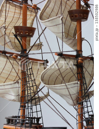 Web of rigging ropes over sails on masts background. Old sailing ship model with wooden masts and sails Web of rigging ropes over sails on masts background. Old sailing ship model with wooden masts and sails 138502986
